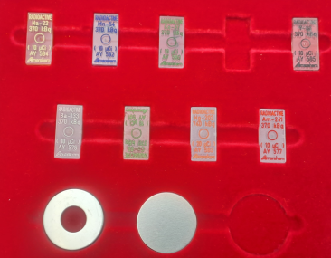 Photo of a set with point-like calibration sources embedded in rectangular plastic matrices and flat, round calibration sources.